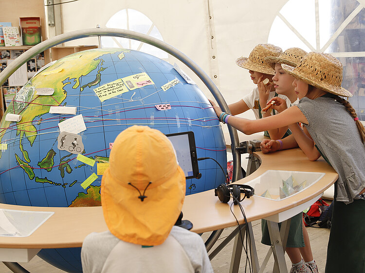 Kinder betrachten eine große Weltkugel im Klimaschutzzentrum