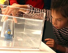 Mädchen experimentiert mit einem Glas und schiebt Luft unter Wasser