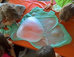 Kinder pusten Luft in eine überdimelsionale Kaugummiblase