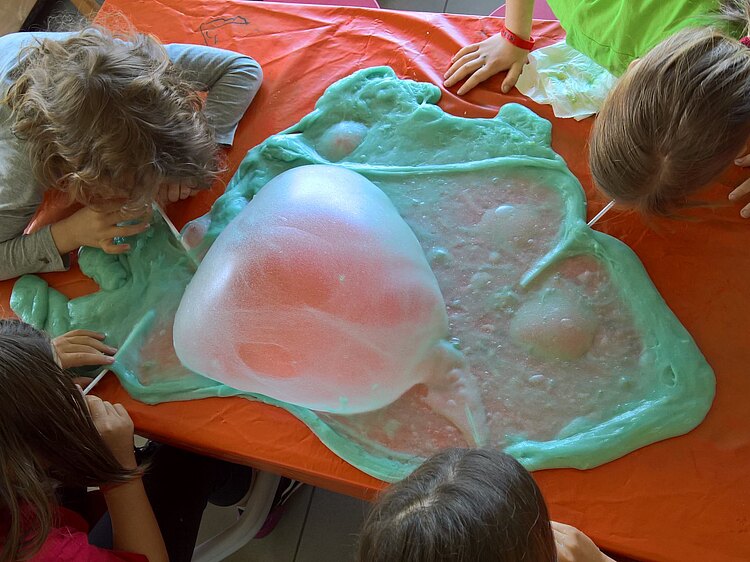 Kinder pusten Luft in eine überdimelsionale Kaugummiblase
