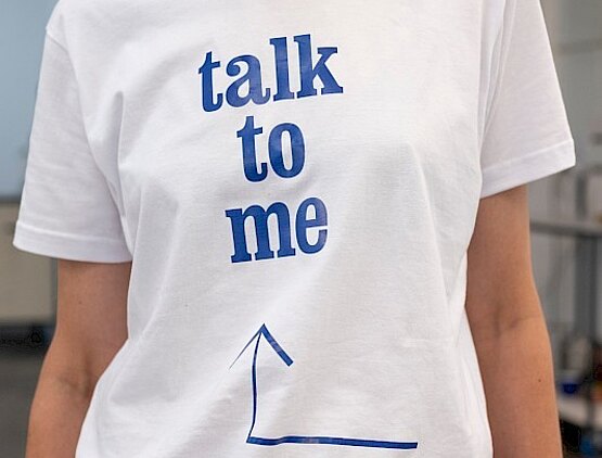 Ansicht einer Frau in weißem T-Shirt mit der Aufschrift talk to me