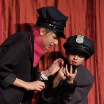 Zwei Mädchen tragen Polizeikappen und spielen auf der Bühne