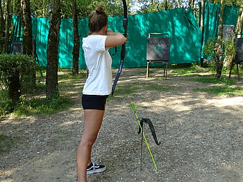 Mädchen schießt mit Pfeil und Bogen auf Zielscheibe