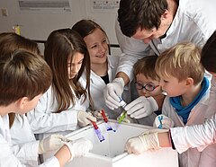 Kinder und ein Mikrobiologe beim Erforschen der Bakterien