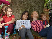 Eine Gruppe Mädchen lehnt an einem Baum und lacht