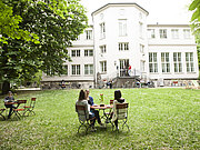 Zwei Menschen sitzen vor dem Alpinen Museum auf Liegestühlen