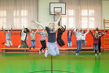 Eine Tanzgruppe springt synchron mit angewinkelten Beinen in die Luft