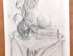 Eine Graphit Zeichnung in Hochformat. Auf der Zeichnung ist ein Stillleben zu erkennen: ein rechteckiger Gegenstand ist im Vordergrund. Auf dem Kasten liegt ein kugeliges Objekt. Eine Vase mit Blumen steht hinter dem Objekt. 