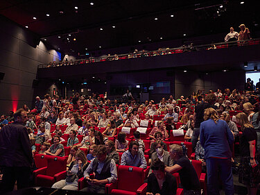 Ein Kinosaal füllt sich mit Publikum.