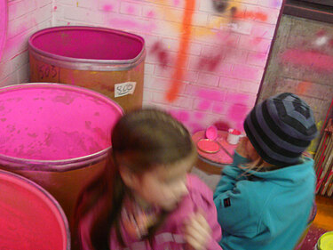 Kinder stehen vor riesigen Tonnen voll Farbe