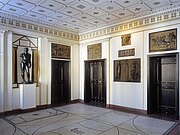 Ein Raum im Inneren der Villa Stuck mit weißen Wänden und goldenen Akzenten und Stuck