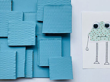 Link neben einer selbst gestalteten Postkarte, auf der ein Monster abgebildet ist, befindet sich eine hellblaue Collage aus Karton.