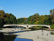 Foto einer Brücke die über die Isar führt mit Personen darunter auf Steinbänken im Wasser